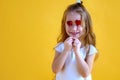 Little girl holding two little red hearts. The concept of Valentine`s Day. Yellow background Royalty Free Stock Photo