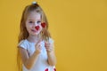 Little girl holding two little red hearts. The concept of Valentine`s Day. Yellow background Royalty Free Stock Photo