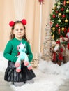 Little girl holding a unicorn in front of christmas tree Royalty Free Stock Photo