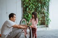 little girl holding a wrench while pedaling with her father Royalty Free Stock Photo