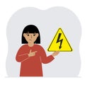 A little girl is holding a yellow warning sign with a black lightning in his hand. The concept of the danger of electric