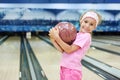 Little girl holds ball in bowling club Royalty Free Stock Photo