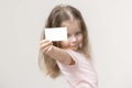 Little girl holds a card in front of her and smile, portrait, copy space Royalty Free Stock Photo