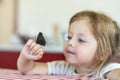 Little girl holds on the hand the Aglais io butterfly and watches for him Royalty Free Stock Photo