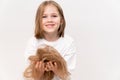 A little girl holds in hands cropped hair after cutting on a white background.