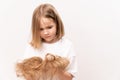 A little girl holds in hands cropped hair after cutting on a white background.