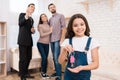 Little girl holds keys to house while realtor shows apartments to young couple.