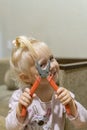 A little girl holds pliers near the front of her face and winks an eye smiling Royalty Free Stock Photo