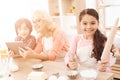 Little girl holds rolling pin and whisk in her hands, sitting in kitchen with her grandmother and grandson. Royalty Free Stock Photo