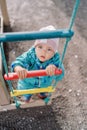 Little girl holds on to the rungs of a rope ladder and looks up. Top view