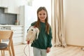 A little girl holds a toy dog under her arm looking into a camera smiling Royalty Free Stock Photo