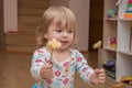 A little girl at home playing with flowers, wearing wooden beads around her neck. Concept: Vaishnava philosophy among Europeans, a