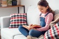 Little girl at home sitting reading book excited