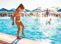 A little girl stands near the pool and tries the water with her foot Royalty Free Stock Photo