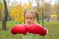A little girl in huge boxing gloves makes an evil face Royalty Free Stock Photo
