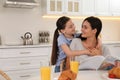Little girl hugging mother in kitchen. Single parenting