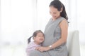 Little girl hugging her pregnant mother belly and smiles Royalty Free Stock Photo