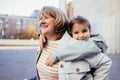 Little girl hugging smiling middle aged woman. Cute female kid and her grandmother enjoy walking outdoors Royalty Free Stock Photo