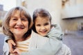 Little girl hugging smiling middle aged woman. Cute female kid and her grandmother enjoy walking outdoors Royalty Free Stock Photo