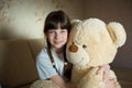 Little girl hugging teddy bear indoor in her room, devotion concept, big bear toy Royalty Free Stock Photo