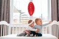 A little girl hugs a boy while sitting together in a white crib. There is a window in the background. Above the bed Royalty Free Stock Photo