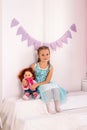 little girl hugs a doll in white room