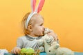 Little girl hugs and kisses Easter bunny on a yellow background