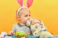 Little girl hugs and kisses Easter bunny on a yellow background. Painted eggs, soft toys for Easter