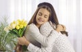 Little girl hugs mommy as she gives her bouquet of yellow tulips on Mother& x27;s Day Royalty Free Stock Photo