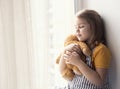 Little girl hugs plush toy empty space background. Friendship and relationship. Caucasian kid dreaming with closed eyes. Emotional