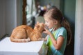 Little girl hugs a red cat in a bright room in the house