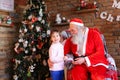 Little girl hugs Santa Claus and makes wish for Christmas in coz Royalty Free Stock Photo