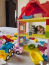 Little girl hugs a tabby cat lying on a bed near a colorful lego house Royalty Free Stock Photo