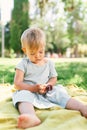 Little girl with ice cream in her hands sits on a bedspread on a green lawn Royalty Free Stock Photo