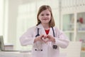 Little girl imitates role of doctor showing heart sign