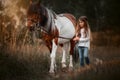 Little girl with in indian style pinto pony in summer field