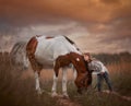 Little girl with in indian style pinto pony in summer field