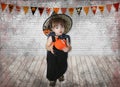 little girl, infant in witch costume with Magic cauldron and Halloween pumpkin