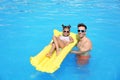 Little girl on inflatable mattress with father in pool