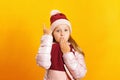 Little girl in a jacket, scarf and hat on a yellow background. The child shows the index finger up Royalty Free Stock Photo