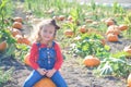 Happy girl sitting on pumpkin at farm field patch Royalty Free Stock Photo