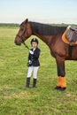 Little girl jockey lead horse by its reins across country in professional outfit Royalty Free Stock Photo