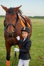 Little girl jockey lead horse by its reins across country in professional outfit Royalty Free Stock Photo