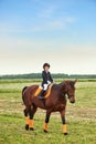 Little girl jockey riding a horse across country in professional outfit Royalty Free Stock Photo