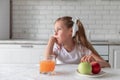 Little girl with juice and fruit apples in the kitchen. healthy food. vegetarianism. the child eats plant food Royalty Free Stock Photo