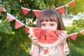 Little girl. Juicy red watermelon slice. Summer sunny day. Bright Grass