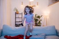 Little girl jumping from the couch in front of TV with remote in hand