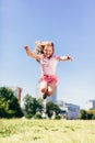 Little girl jumping high in the city park in colorful dirty clothes.