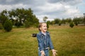 Little girl jumping and throwing green grass on lawn in spring park. Happy joyfull emotion, carefree childhood, outdoors activity