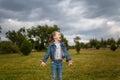 Little girl jumping and throwing green grass on lawn in spring park. Happy joyfull emotion, carefree childhood, outdoors activity.